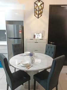 Il comprend une cuisine équipée d'une table blanche avec des chaises et d'un réfrigérateur. dans l'établissement 1308 Almas suites Lavender Netflix 100mbps By STAY, à Nusajaya