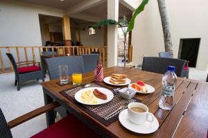 einen Holztisch mit Tellern aus Essen und einer Tasse Kaffee in der Unterkunft Tropic Tree Maldives in Gulhi