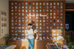una joven parada frente a un muro de buenos días en Good Ol' Days Hotel en Busan