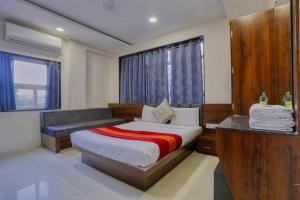 a bedroom with a bed with a bench and a window at Hotel Kumar Atithi Nivas in Indore