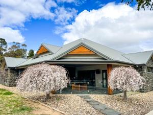 a house with two trees in front of it at Hamilton House - Snowy Mountain Luxury Villas in Jindabyne