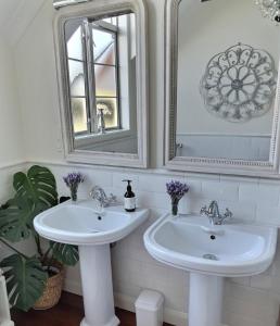 a white bathroom with two sinks and a mirror at Lavender Lodge in Tauranga