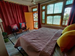 1 dormitorio con cortinas rojas, 1 cama y 1 silla en The Hidden Tribe en Bīr
