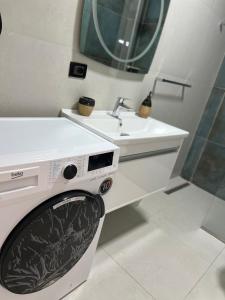 AmIon Apartment in Center of Tirana في تيرانا: وجود غسالة ملابس في الحمام بجانب مغسلة +57 صورة