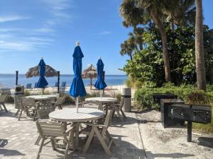 Fun-N-Sun with Spectacular Ocean Views في تامبا: مجموعة طاولات مع مظلات زرقاء على الشاطئ