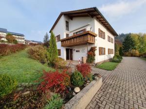 ein Haus mit einem Balkon und einer Ziegelsteinfahrt in der Unterkunft Germanus Ferienwohnung in Warmensteinach