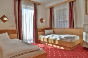 a hotel room with two beds and a window at Pension Posauner in Dorfgastein