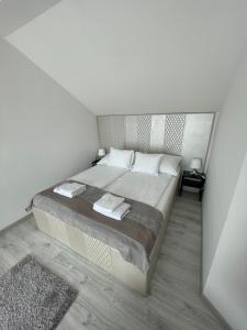 - une chambre avec un grand lit aux murs blancs dans l'établissement Martina apartman, à Gyula