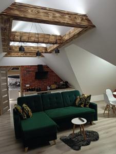 a living room with a green couch and a brick wall at Apartament Nasze Poddasze in Ciche