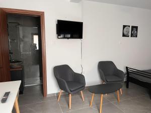 uma sala de estar com duas cadeiras, uma mesa e uma televisão em Maria's Apartment 2 em Galata