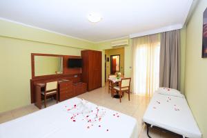 a bedroom with two beds and a desk and a mirror at Esmeralda Hotel in Kremasti