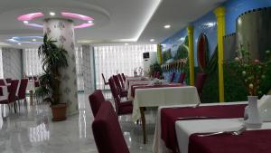 a restaurant with tables and chairs and a painting on the wall at Miroglu Hotel in Diyarbakır