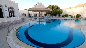 a large blue swimming pool with an umbrella at Falaj Daris Hotel in Nizwa