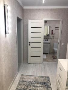 ein Badezimmer mit einer weißen Tür und einem Spiegel in der Unterkunft Уютная квартира в центре города с современным дизайном in Qostanai