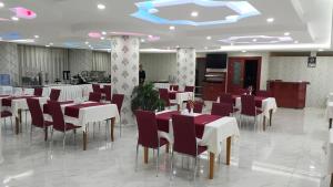 a dining room with red and white tables and chairs at Miroglu Hotel in Diyarbakır