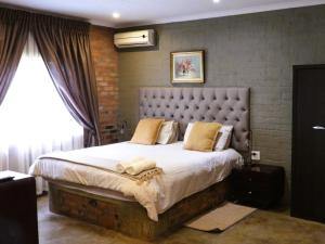 um quarto com uma cama grande e uma parede de tijolos em Maretlwane Guesthouse em Buffelspoort