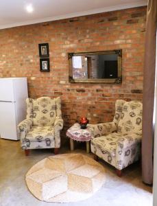 uma sala de estar com duas cadeiras e um espelho em Maretlwane Guesthouse em Buffelspoort