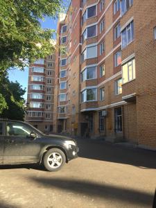 um carro preto estacionado em frente a um edifício em Уютная, новая квартира в центре города em Qostanay