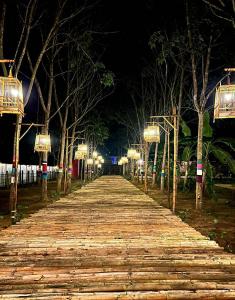 a long boardwalk with lights on it at night at ฮักฮิมเกี๋ยน รีสอร์ท น่าน Hug Him Kien in Nan
