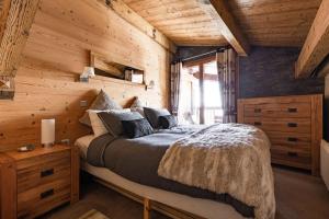 1 dormitorio con 1 cama y pared de madera en Luxury Avoriaz Chalet with hot tub en Avoriaz