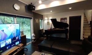 a living room with a flat screen tv and a piano at Avanti Chalet 白馬 in Hakuba
