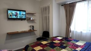 a bedroom with a bed and a tv on the wall at Gowrie Agapanthus in Singleton