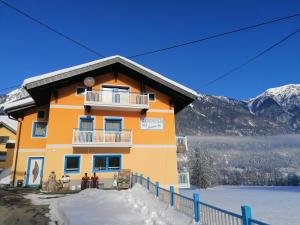 a building with people standing in front of it in the snow at Haus Manuela am Pressegger See in Egg