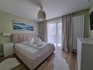 ein Schlafzimmer mit einem Bett und einem großen Fenster in der Unterkunft Eminescu Premium Luxury Apartments in Buşteni