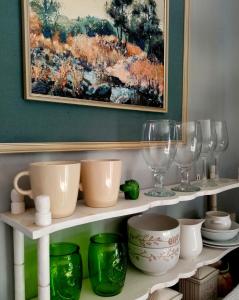 un estante con platos y vasos y una pintura en Lavender Cottage, en Ciudad del Cabo