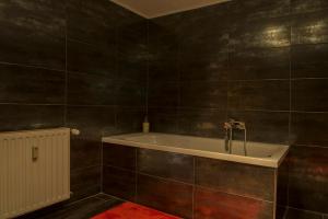a bathroom with a bath tub with black tiles at Apartment Alma in Quedlinburg
