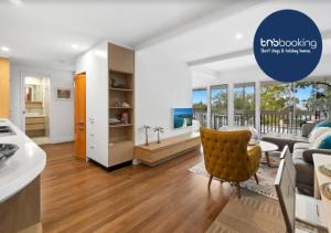 a living room with a couch and a chair at Seaviews Little Cove Beach Noosa 2BR 200m to beach in Noosa Heads +16 photos