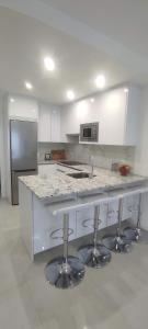 a white kitchen with a counter and stools in it at Piso en el Centro de La Cala in Mijas Costa