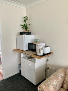 a living room with a shelf with a microwave and a couch at Large relaxing light filled room in Bowral in Bowral
