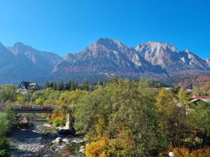 a bridge over a river with mountains in the background at Eminescu Premium Luxury Apartments in Buşteni