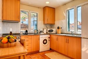 a kitchen with wooden cabinets and a table with a bowl of fruit at Largo dos Milagres, a Home in Madeira in Machico