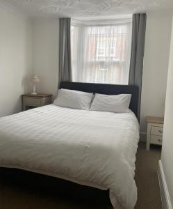 a bedroom with a large white bed with a window at Amaya Two - Spacious, ground floor apartment with a large patio area. in Lincolnshire