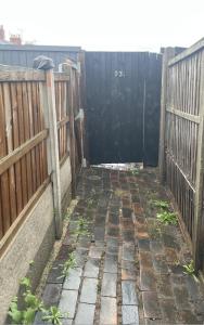 a patio with a fence and a gate with weeds at Amaya Two - Spacious, ground floor apartment with a large patio area. in Lincolnshire