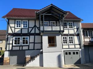 a white and black house with a balcony at Ferienwohnung Ederblick in Wabern