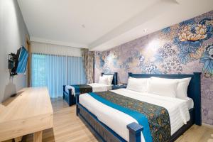 a hotel room with two beds and a tv at Bhukitta Boutique Hotel Phuket Town in Phuket