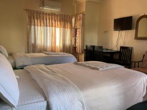 ein Hotelzimmer mit 2 Betten und einem Tisch mit einem TV in der Unterkunft Trekkers Lodge in Pokhara