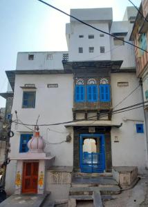 a white building with blue windows and a red door at Madan Mohan Villas (A Haritage Haveli Home Stay) in Udaipur