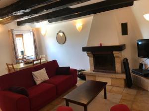 ein Wohnzimmer mit einem roten Sofa und einem Kamin in der Unterkunft La Metairie & Cottages in Camors