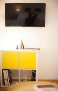 a television on a wall above a shelf with books at Luxor 7 in Seville +3 photos