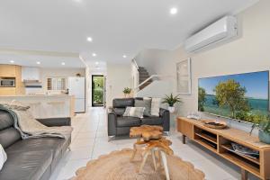 a living room with a couch and a tv at Tropical Retreat in 2 Bedroom Townhouse in Noosaville