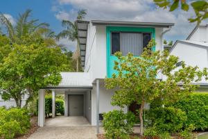 a white house with a green door and trees at Tropical Retreat in 2 Bedroom Townhouse in Noosaville