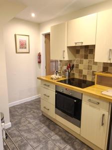 a kitchen with white cabinets and a stove top oven at Cosy cottage in the heart of Pateley Bridge. in Pateley Bridge