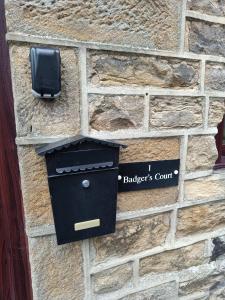 a box on a brick wall with a mailbox at Cosy cottage in the heart of Pateley Bridge. in Pateley Bridge