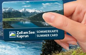 uma mão segurando um cartão de férias com um lago e montanhas em AlpinResort Kaprun 2 em Kaprun