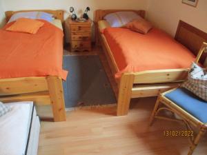 a bedroom with two twin beds and a chair at Haus mit Lilie und Rose in Westerdeichstrich