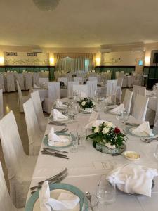 un comedor con mesas blancas y sillas blancas en Hotel Casa Del Gourmet, en Siderno Marina